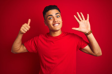 Naklejka premium Young brazilian man wearing t-shirt standing over isolated red background showing and pointing up with fingers number six while smiling confident and happy.