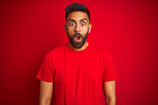 Young handsome indian man wearing t-shirt over isolated red background afraid and shocked with surprise expression, fear and excited face.