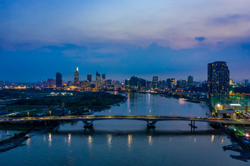 Classic aerial night river view of the Ho Chi Minh City, Vietnam financial district from Binh Thanh district with bridge across the Saigon river carrying evening traffic