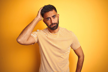 Young indian man wearing t-shirt standing over isolated yellow background worried and stressed...