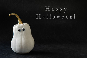 White angry pumpkin with googly eyes on black background with text Happy Halloween. Minimalist concept, pop art. Horizontal