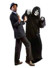 Man in a grim reaper halloween ghost costume having fun and scaring a grown businessman in a suit. ...