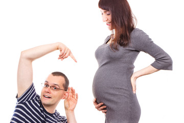 Amazed father listening and showing belly of his pregnant wife, expecting for newborn