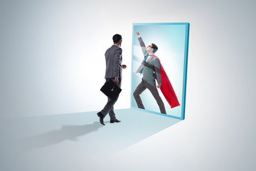 Businessman seeing himself in mirror as superhero