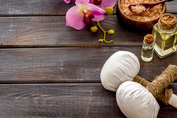 Massage thai herbal balls near spa accessories and orchids on dark wooden background copy space