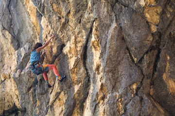 A girl climbs a rock.