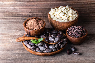 Cocoa products in wooden bowls spoon on old rustic background.