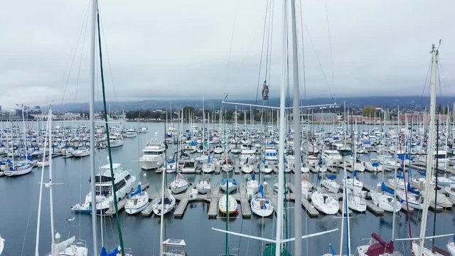 Sail boats in their slips in a Marina on a cloudy day with slight rain.