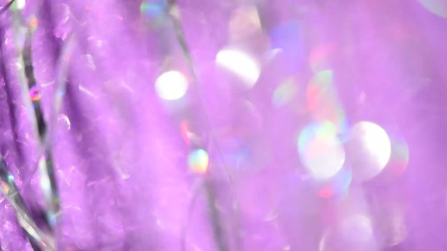 Abstract blurred background with moving particles of glitter, sparkles and Christmas tinsel for festive design.
