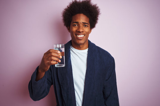 African American Man Wearing Pajama Drinking Glass Of Water Over Isolated Pink Background With A Happy Face Standing And Smiling With A Confident Smile Showing Teeth