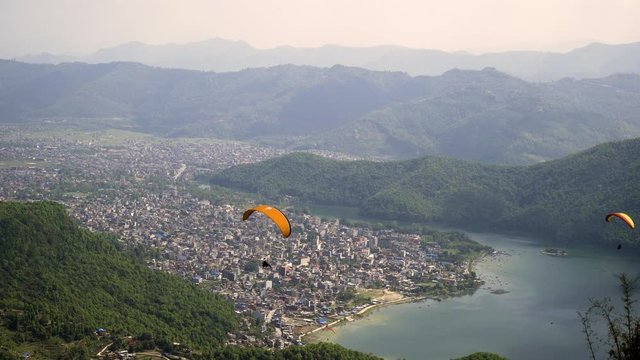 Paragliders flying against the Himalayas , Pokhara , Nepal.