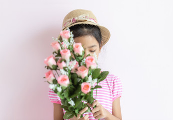 The child wears a hat and holds a bouquet of flowers covering her face