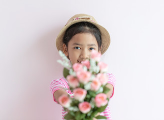The child wears a hat and holding roses flowers with smiling and happy