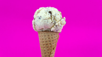 Cookies & Cream ice cream scoop in waffle cone on Pink background, Closeup Front view Food concept..