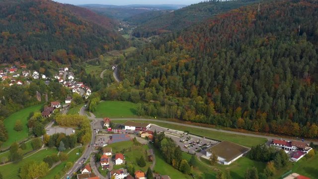 Aerial view of the city Bad Herrenalb in Germany on a sunny day in autumn, fall. Zoom in on the town entrance and mountains.