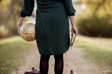 Female holding a desk globe and the bible while standing on empty pathway with blurred background