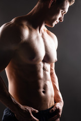 Strong, fit and sporty bodybuilder man over dark background. Sport and fitness.