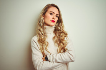 Naklejka premium Beautiful woman wearing winter turtleneck sweater over isolated white background looking to the side with arms crossed convinced and confident