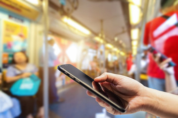 Female use hand holding smartphone with empty screen blurred images touch of Abstract blur in the BTS Skytrain Station at Bangkok, Thailand,the big city travel lifestyle transportation concept
