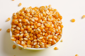 Dried corn seeds in bowl on white background 