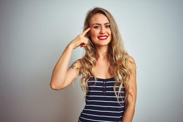 Fototapeta premium Young beautiful woman wearing stripes t-shirt standing over white isolated background Smiling pointing to head with one finger, great idea or thought, good memory