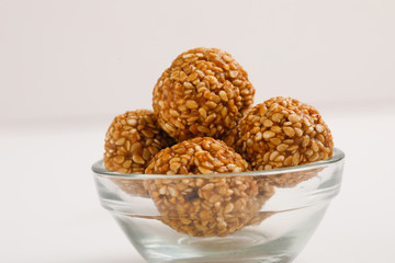 Indian sweet Sesame seeds ball or called in Hindi til ke laddu in glass bowl on white background 