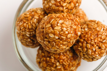 Indian sweet Sesame seeds ball or called in Hindi til ke laddu in glass bowl on white background 
