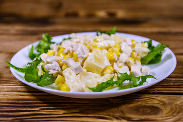 Festive salad with chicken breast, canned pineapple, cheese, sweet corn and mayonnaise on wooden table