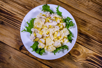 Festive salad with chicken breast, canned pineapple, cheese, sweet corn and mayonnaise on wooden table. Top view