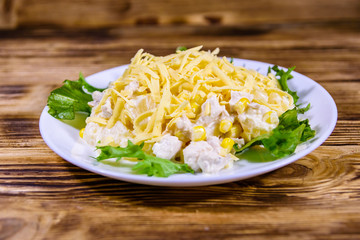 Festive salad with chicken breast, canned pineapple, cheese, sweet corn and mayonnaise on wooden table
