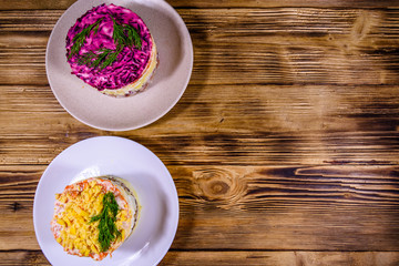 Traditional russian new year layered salads Mimosa and Herring under a fur coat (shuba) on wooden table. Top view