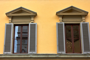 Facade of house with yellow - orange wall, windows with shutters in Firenze, Italy.
