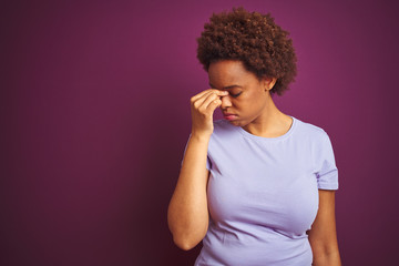 Fototapeta na wymiar Young beautiful african american woman with afro hair over isolated purple background tired rubbing nose and eyes feeling fatigue and headache. Stress and frustration concept.