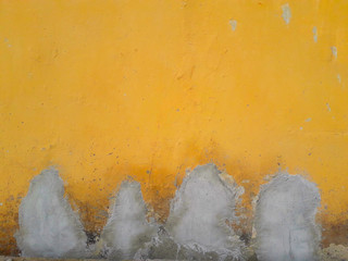 The wall made of damaged cement has been repaired with a new cement plaster from the original wall painted yellow.
