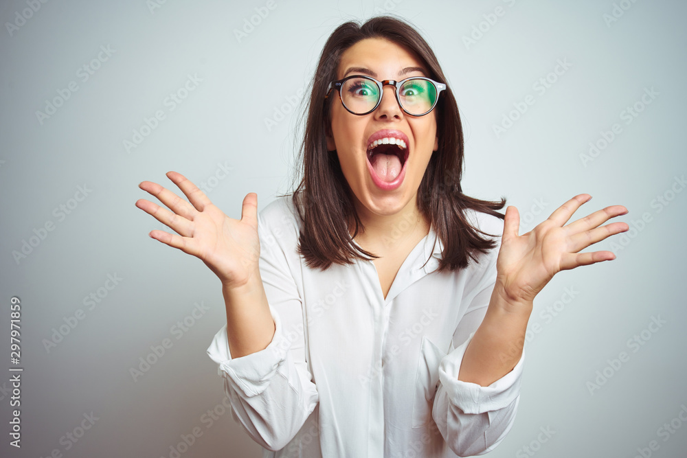 Canvas Prints young beautiful business woman wearing glasses over isolated background celebrating crazy and amazed