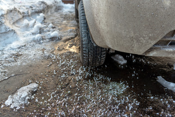Winter tire with spikes on the front of the off-road car stands on winter ice with snow and...