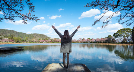 Young woman enjoying freedom with open hands in front of lake
