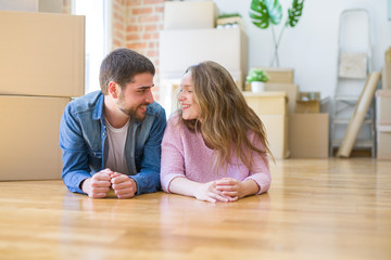 Young beautiful couple in love relaxing lying on the floor together with cardboard boxes around for moving to a new house