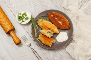 Plate with fried pies and wooden rolling pin on table.