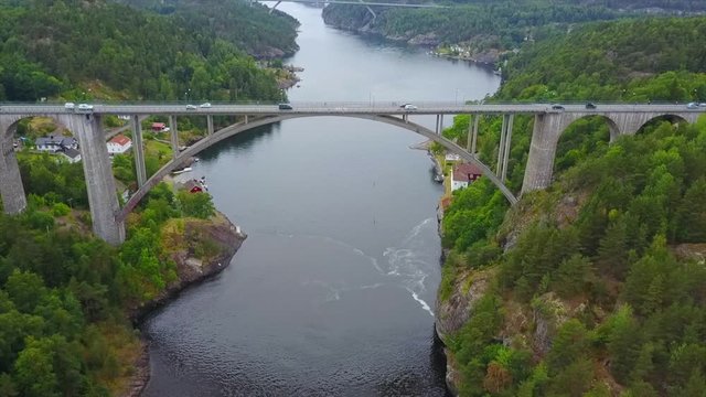 Cars driving on stone bridge spanning an inlet, aerial revealing view of Svinesund bridge in Norway, engineering, construction and transportation concept
