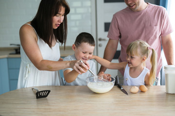 Obraz na płótnie Canvas Funny family preparing dough in the kitchen