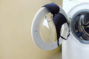 Black bra or black uplift on door the front-loading washing machine. - obrazy, fototapety, plakaty