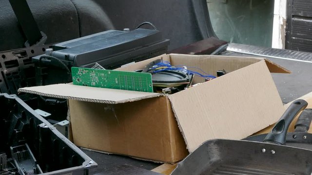 Closeup POV exterior shot of a man loading an estate car / station wagon with unwanted items to be disposed of.