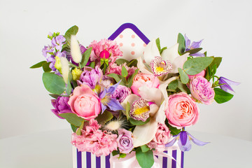 Bouquet of different flowers in a striped purple-gray box