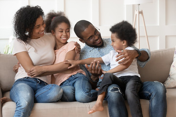 Happy black family relax on couch at home cuddling