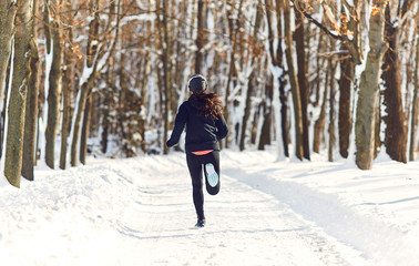 A girl runs through the park in winter