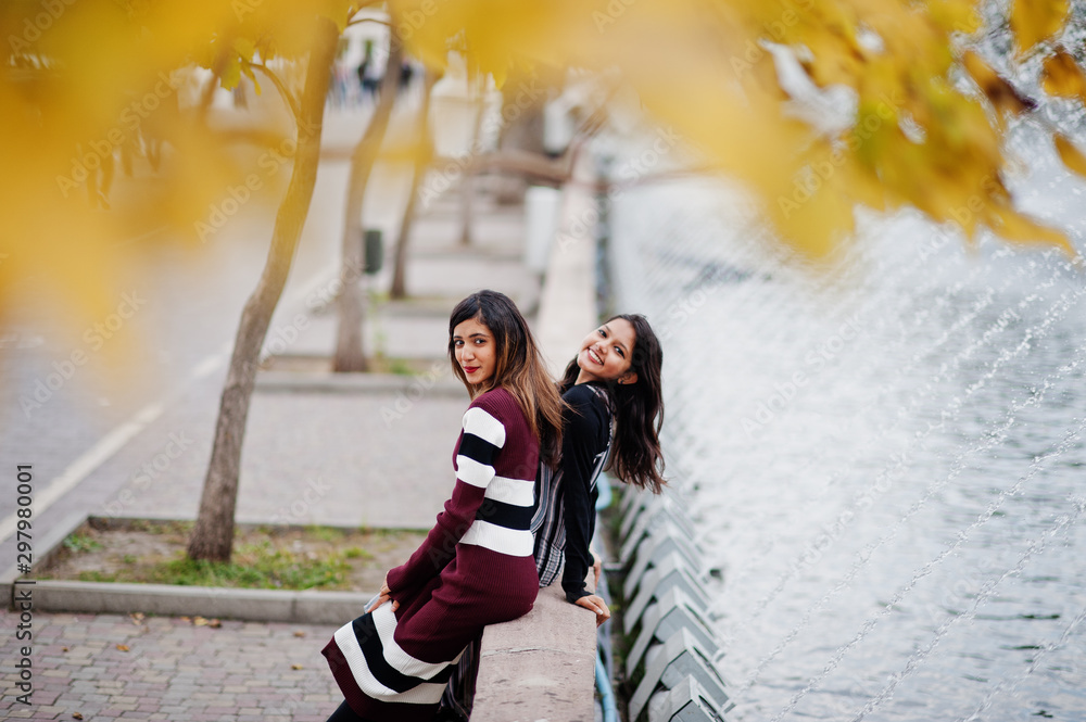 Wall mural portrait of two young beautiful indian or south asian teenage girls in dress posed at autumn park.