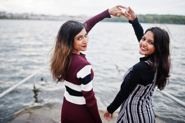 Portrait of back two young beautiful indian or south asian teenage girls in dress show  joined...