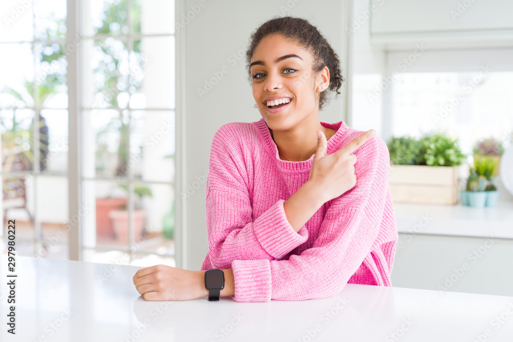 Sticker Beautiful african american woman with afro hair wearing casual pink sweater cheerful with a smile on face pointing with hand and finger up to the side with happy and natural expression