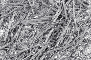 Top down view of bundles of grey colored polypropylene fiber for concrete structural reinforcement on white. Macro construction themed background texture